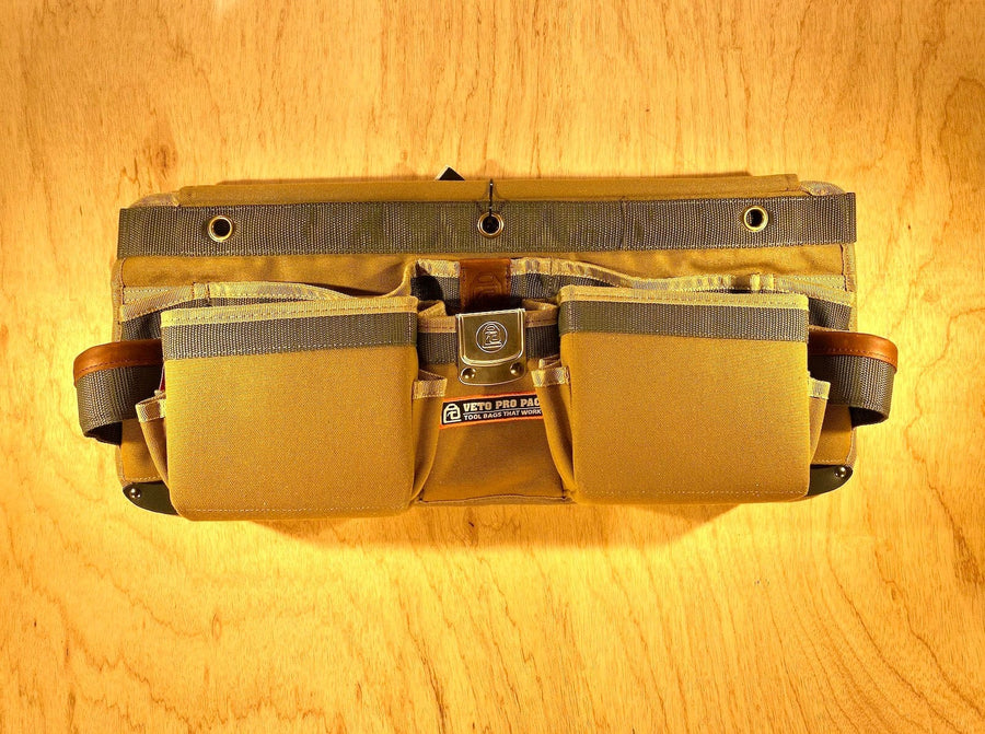A VET Veto Pro Pac TA-WBX Waist Apron with boxed pockets, made from durable tan polyester canvas and featuring multiple compartments and pockets, lying on a wooden surface.